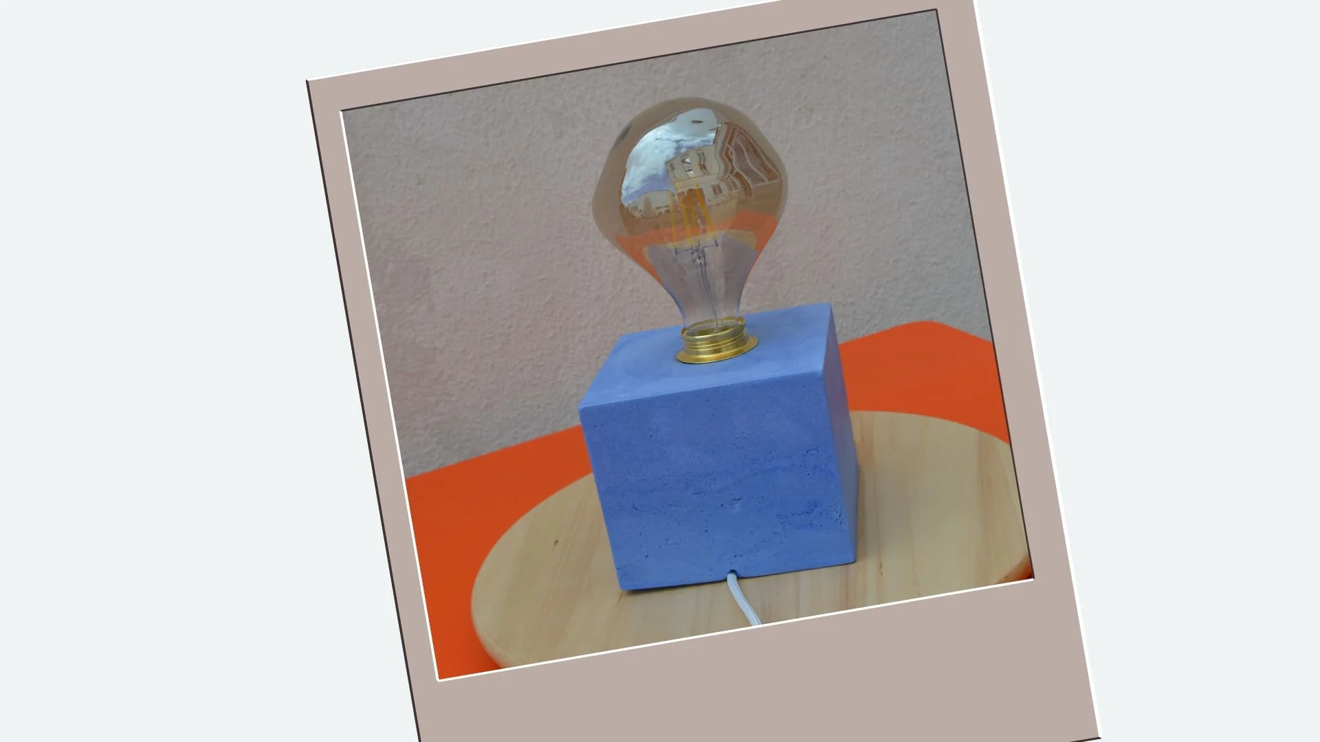 Lampe en béton bleu coulé dans un cadre. La prise de vue met en valeur les plus jolies imperfections de la matière.