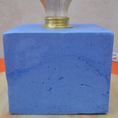 Vue de côté de la lampe artisanale en béton bleu